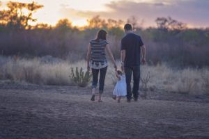 back view of a couple walking outdoors with their little girl