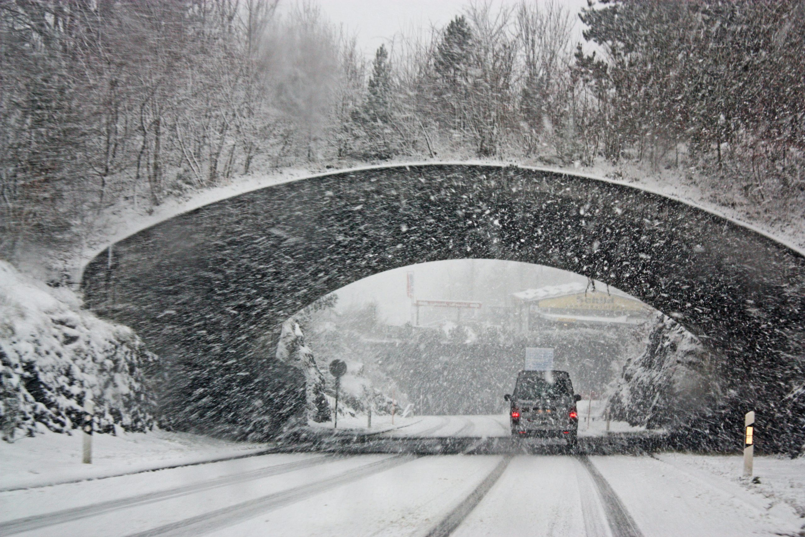 Car driving through the snow under a bridge
